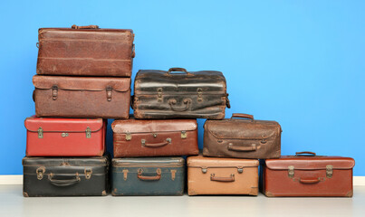 Vintage Collection of Stacked Suitcases in Various Sizes and Colors Against a Bright Blue Background for Travel and Nostalgia Themes