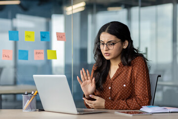 Calm and serious woman talking remotely with colleagues using laptop for video call. Businesswoman...