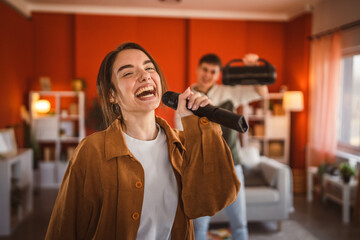 young woman hold microphone and sing karaoke have fun at home