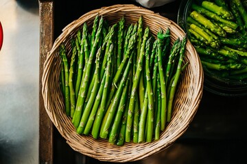 Freshly harvested asparagus arranged in a rustic basket at a bustling market