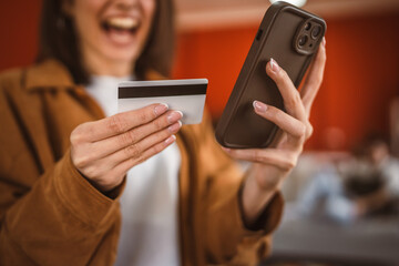 close up on female hands hold mobile phone and credit card at home