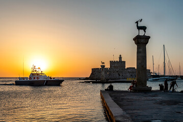 Sunrise over the harbor of Rhodes old town. Entrance to Port of Rhodes at first sunlight. Rhodes...