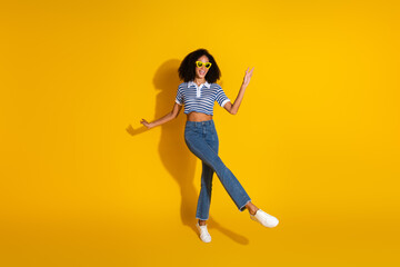 Stylish Young Woman in Casual Clothing Posing Against a Vibrant Yellow Background, Showcasing Trendy Fashion and Joyful Energy