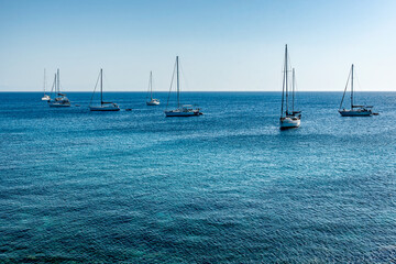 Sailboats at sunrise in the Mediterranean Sea off the coast of Mandraki harbor. Rhodes Island. Greece