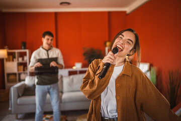 young woman hold microphone and sing karaoke have fun at home