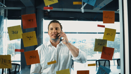 Professional businessman making phone call to customers while looking at marketing strategy idea...
