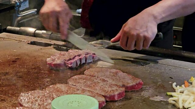 Close up-Unidentified chef cutting and cooking meat on commercial grill