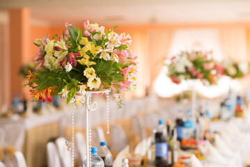 Fresh floral centerpiece with lilies and roses on wedding table