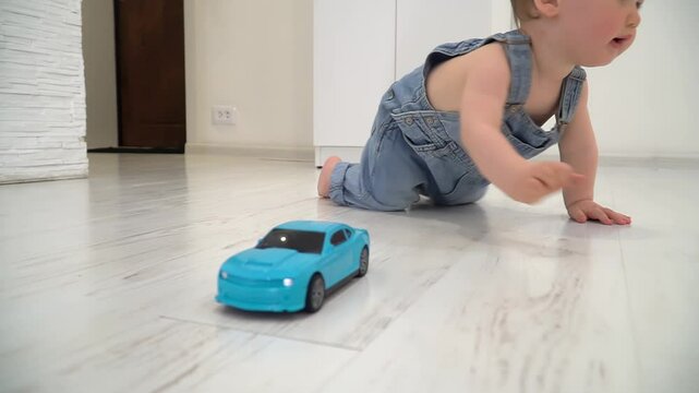 Toddler boy crawling on a light-colored wooden floor inside a home.