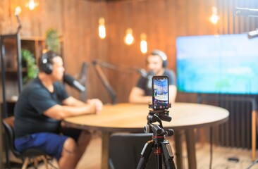Two individuals share insights and stories in a stylish podcast studio equipped with microphones...
