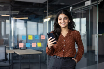 Successful satisfied woman with phone in hands smiling and looking at camera. Office worker...
