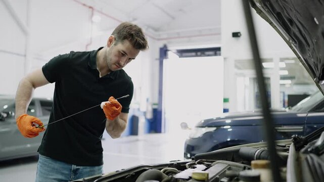 Mechanic checking oil level in car engine