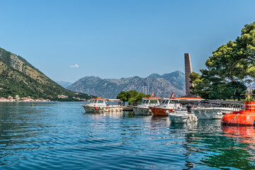 Boats docked at the serene Bay of Kotor with mountainous landscapes in the background. Calm waters...
