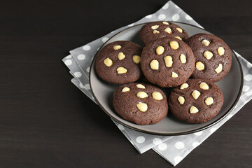 Delicious chocolate cookies with hazelnuts on black wooden table