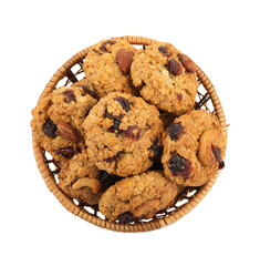 Delicious oatmeal cookies with dried cranberries and nuts in wicker basket isolated on white, top view
