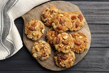 Tasty cookies with nuts on dark wooden table, top view