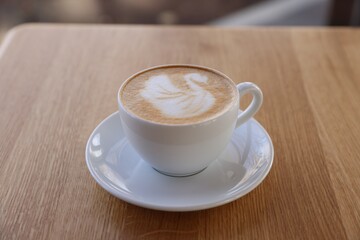 Cup of aromatic coffee on wooden table in cafe, closeup
