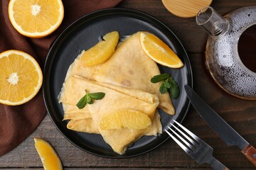 Delicious Crepes Suzette served on wooden table, flat lay