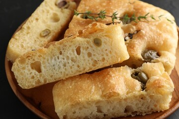 Slices of delicious focaccia bread with olives, thyme and salt on table, closeup