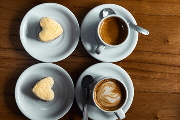 cornstarch alfajor with dulce de leche and coconut in the shape of a heart and coffee plus coffee with milk