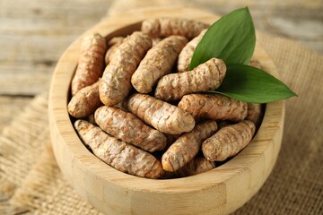 Tumeric rhizomes with leaves in bowl on table, closeup