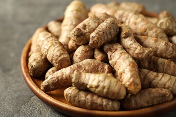 Raw tumeric rhizomes on grey table, closeup