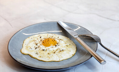 Breakfast served on the kitchen table with a fried egg on a plate