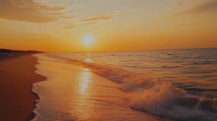 Aerial view of a serene beach showcasing gentle waves under a vibrant sunset, creating a tranquil and picturesque atmosphere.