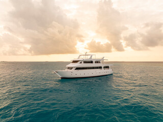 Unmarked white ship in the ocean at the sunset time.