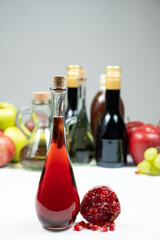 Pomegranate vinegar against the background of fruits and other types of vinegars
