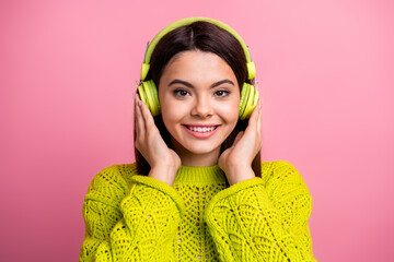 Charming Woman Listening to Music With Headphones in a Stylish Knit Sweater Against a Pink...