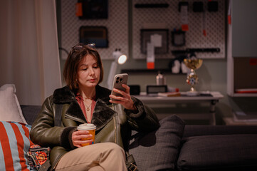 Woman Relaxing on Couch Using Smartphone and Drinking Coffee