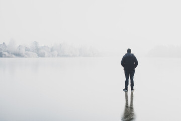 Obraz premium Silhouette of alone man standing on winter fog and ice background. Concept of psychology, guy thinking about something