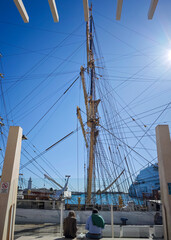 Fototapeta premium Pareja sentada en el muelle uno del puerto de Málaga frente a un velero antiguo
