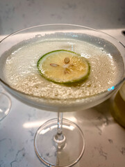 Refreshing cocktail with lime, grape garnish, and frothy texture in elegant glassware