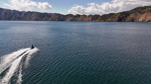 Vista panor&aacute;mica de lago profundo entre monta&ntilde;as con lancha r&aacute;pida dejando estela.