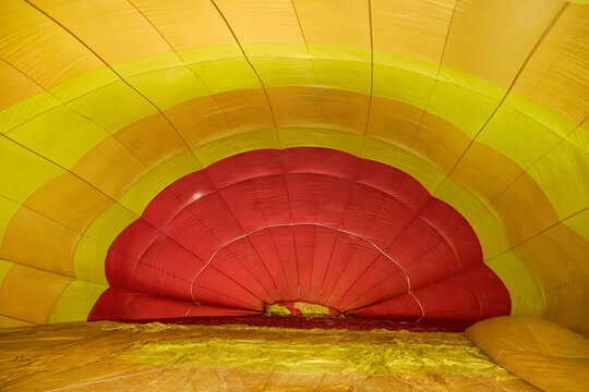 Inside view of a colorful hot air balloon being inflated, showcasing vibrant yellow and red patterns