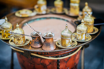 Traditional Turkish coffee set with ornate golden cups and copper cezve on sand heater. Authentic Middle Eastern coffee preparation in a vintage style. Cultural and hospitality concept