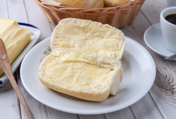 French bread or salt bread with butter and coffee over white wooden table