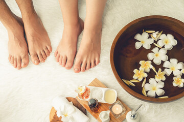 Couple indulges in blissful foot massage at luxurious spa salon for reflexology therapy in gentle day light ambiance resort or hotel foot spa. Quiescent