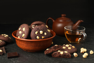 Tasty chocolate cookies with hazelnuts and tea on black table