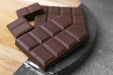 Pieces of delicious dark chocolate on brown table, closeup