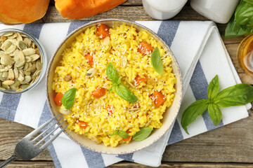 Delicious pumpkin risotto served on wooden table, flat lay