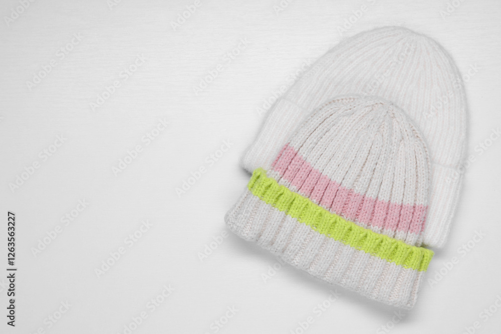 Sticker Stylish knitted hats on white background, top view. Space for text