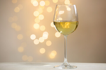 Tasty white wine in glass on table against grey background with blurred lights, bokeh effect. Space for text