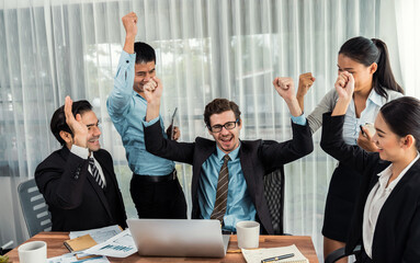 Group of happy businesspeople in celebratory gesture and successful efficient teamwork. Diverse race office worker celebrate after made progress on marketing planning in corporate office. Meticulous