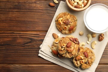 Tasty cookies with nuts and milk on wooden table, flat lay. Space for text