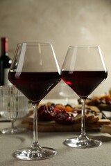 Red wine and different snacks served on light grey table