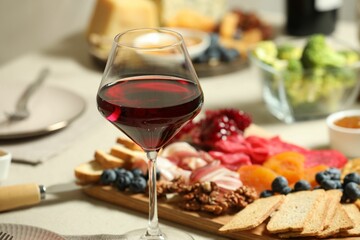 Red wine and different snacks served on table, closeup