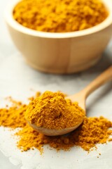 Turmeric powder and spoon on light grey table, closeup